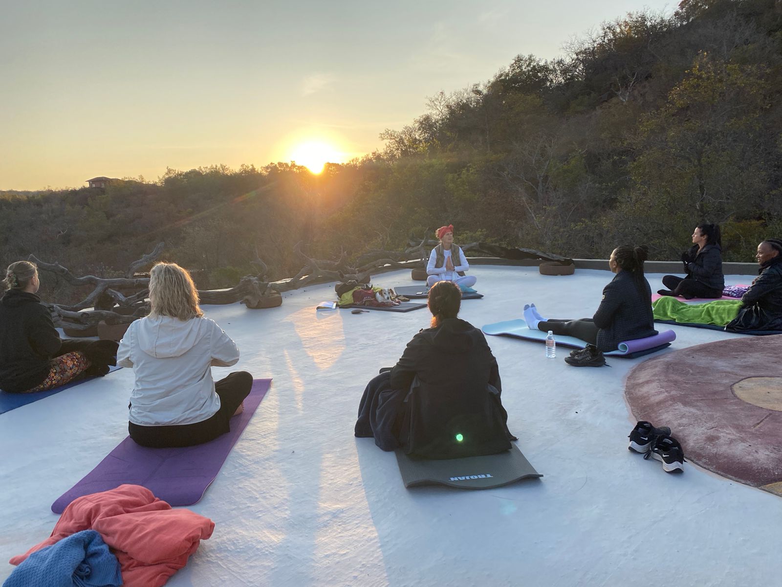 A sunrise meditation circle on the open-air deck at Bela-Bela — guests seated in stillness as the sun rises over the bushveld, held in sacred space.